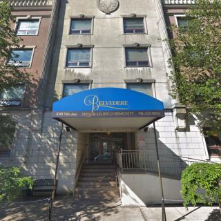 An urban residential building with a blue awning at the entrance.