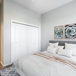 A modern bedroom with a comfortable bed, decorative pillows, and artwork on the wall.