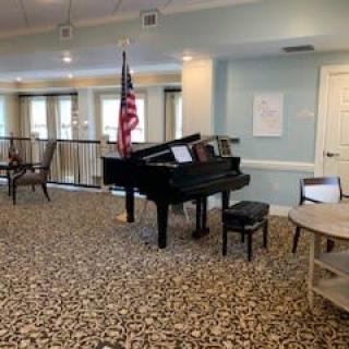 A cozy room featuring a grand piano and an American flag.