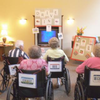 Residents in a community center enjoying a group activity while seated in wheelchairs.