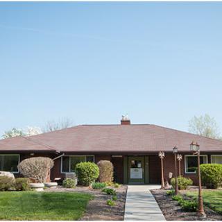 A charming single-story house with well-maintained landscaping and a clear blue sky.