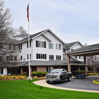 A residential building with a driveway, featuring a parked car and an American flag in the foreground.