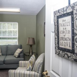 A cozy living room with a sign on the door that reads, 'Our Family is a Circle of Strength and Love'.