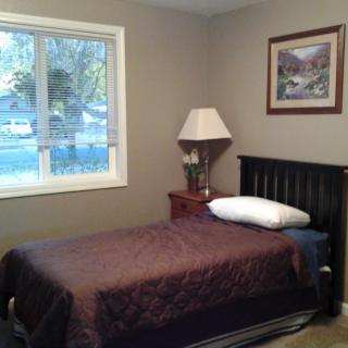 A cozy bedroom with a single bed, nightstand, and window.