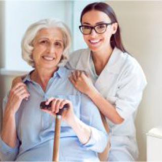 A caregiver smiling with an elderly woman at home.