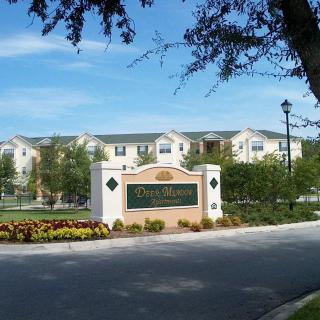 Entrance to an apartment complex with well-maintained landscaping and a visible sign.