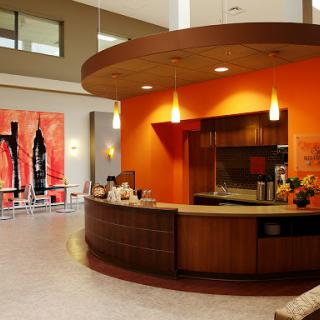 A modern reception area featuring an orange accent wall, wooden counters, and contemporary artwork.