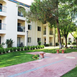 A well-maintained apartment complex with lush green surroundings and a paved walkway.