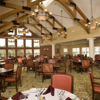 Spacious dining area with elegant table settings and wooden ceiling beams.