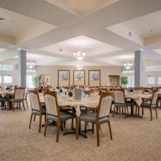 Spacious dining area with neatly arranged tables and chairs, well-lit by ceiling lights.