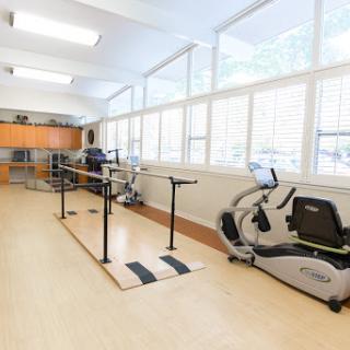 A well-lit rehabilitation gym equipped with exercise bars and fitness machines.
