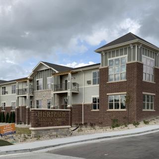 A modern two-story apartment building with a brick facade under a cloudy sky.
