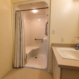 A well-lit bathroom featuring a shower, bathtub, and sink.