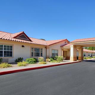 A single-story building with a prominent entrance and well-maintained landscaping under a clear blue sky.