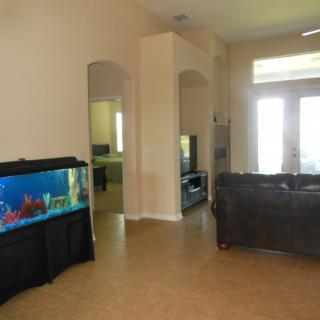A cozy living room featuring an aquarium, sofa, and a television.