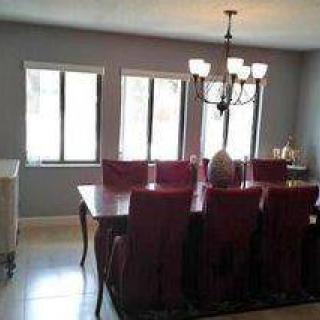 A dining room with a large table, red chairs, and a chandelier.