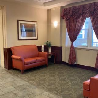 A cozy lobby seating area with red sofas, decorative curtains, and a framed painting on the wall.