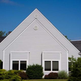 A suburban house with a gable roof and white siding.