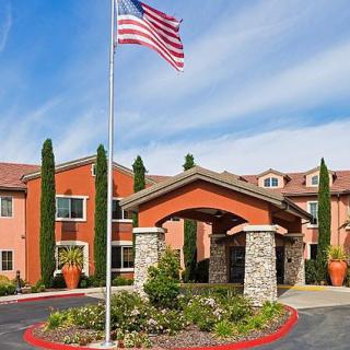 A building with an entrance and landscaping, featuring a flagpole with the American flag waving above.