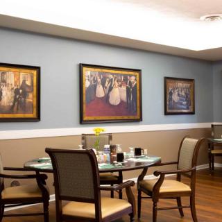 A cozy dining area with elegantly framed paintings and neatly arranged tables and chairs.