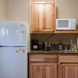 A compact kitchen area with a refrigerator, microwave, coffee maker, and sink.