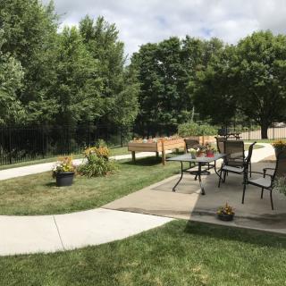 A peaceful backyard with a patio area, outdoor furniture, and lush greenery.