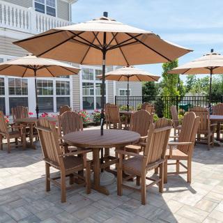A patio area with wooden tables and chairs under large umbrellas.