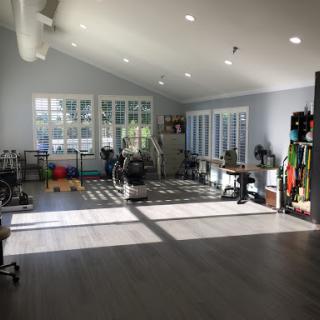 A well-lit gym space with multiple exercise equipment and large windows.