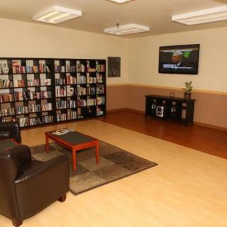 A cozy library corner with bookshelves, comfortable seating, and a television.