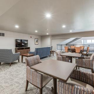 A modern lounge area with comfortable seating, a television, and a carpeted floor.