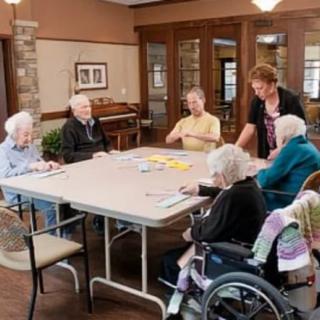 A group of seniors engaging in an activity around a table in a nursing home.