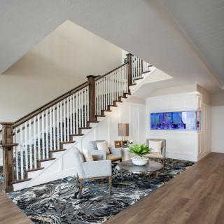 A modern living room with a stylish staircase, featuring elegant furniture and contemporary artwork.