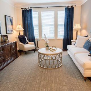 A cozy and well-decorated living room with a sofa, armchair, coffee table, and elegant lighting.