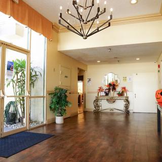 A well-lit lobby area featuring a wooden floor, elegant chandelier, and decorative elements.