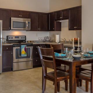 A modern kitchen and dining area with stainless steel appliances and a neatly set dining table.