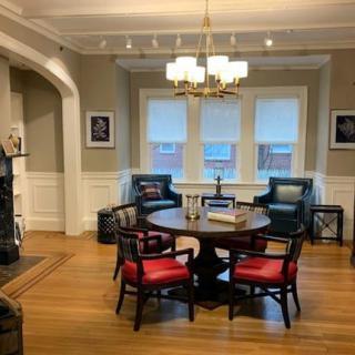 A cozy living room with a round table, red and black chairs, and a chandelier.
