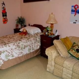 A cozy bedroom with a bed, couch, and a lamp.