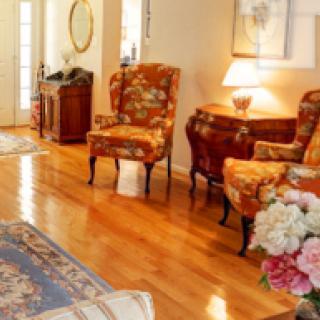 A cozy living room with hardwood floors, traditional armchairs, and a warm table lamp.
