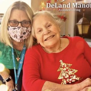 An elderly woman and a caregiver smiling together at DeLand Manor Adult Living.