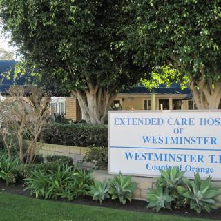 Entrance sign for Extended Care Hospital of Westminster surrounded by trees and landscaping.