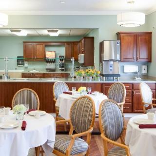 A cozy dining room with elegantly set tables and a view of the adjoining kitchen area.