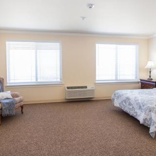 A spacious bedroom with a large bed, two windows, and comfortable seating.