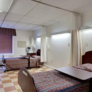 A view of a shared patient room in a hospital, featuring two beds and basic amenities.