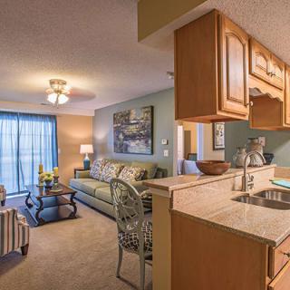 A cozy apartment interior featuring a living room and kitchen area with modern furniture and warm lighting.