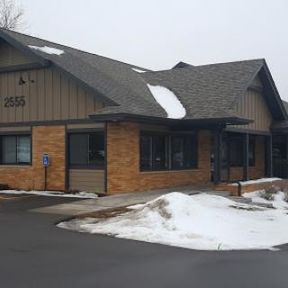 A modern building with a combination of brick and siding, partially covered in snow.