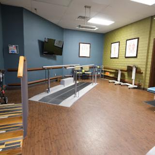 A spacious rehabilitation therapy room equipped with walking aids and a warm, welcoming atmosphere.