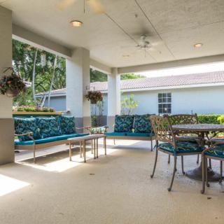 A spacious covered patio with comfortable seating and a dining table, surrounded by lush greenery.