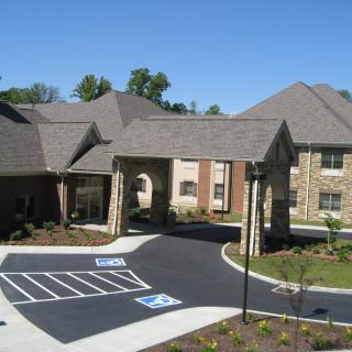 A residential building with a parking lot and landscaped surroundings.