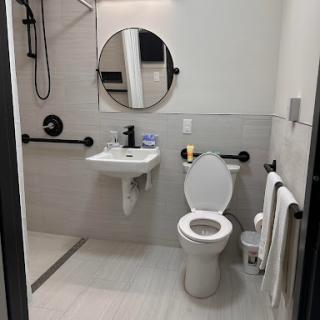 A modern bathroom featuring accessibility features including grab bars and a spacious layout.