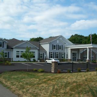 A large suburban house with a well-maintained lawn under a partly cloudy sky.
